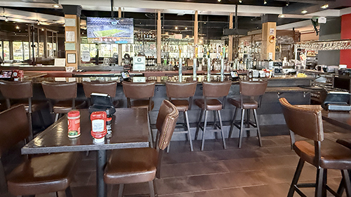 Curved Red Robin bar with stools, tables, televisions, and beverage taps