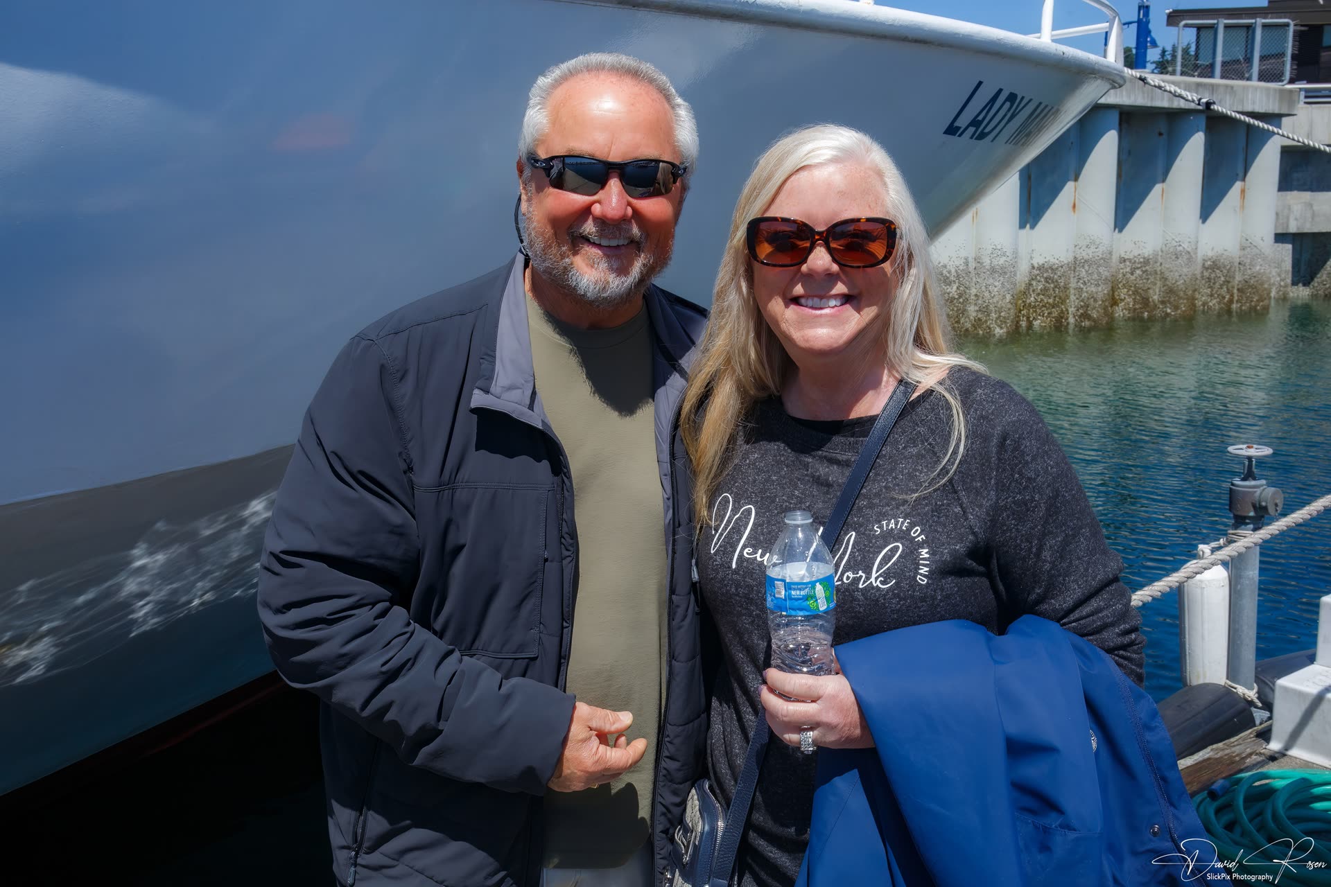 Two cruise guests pose together beside the vessel.
