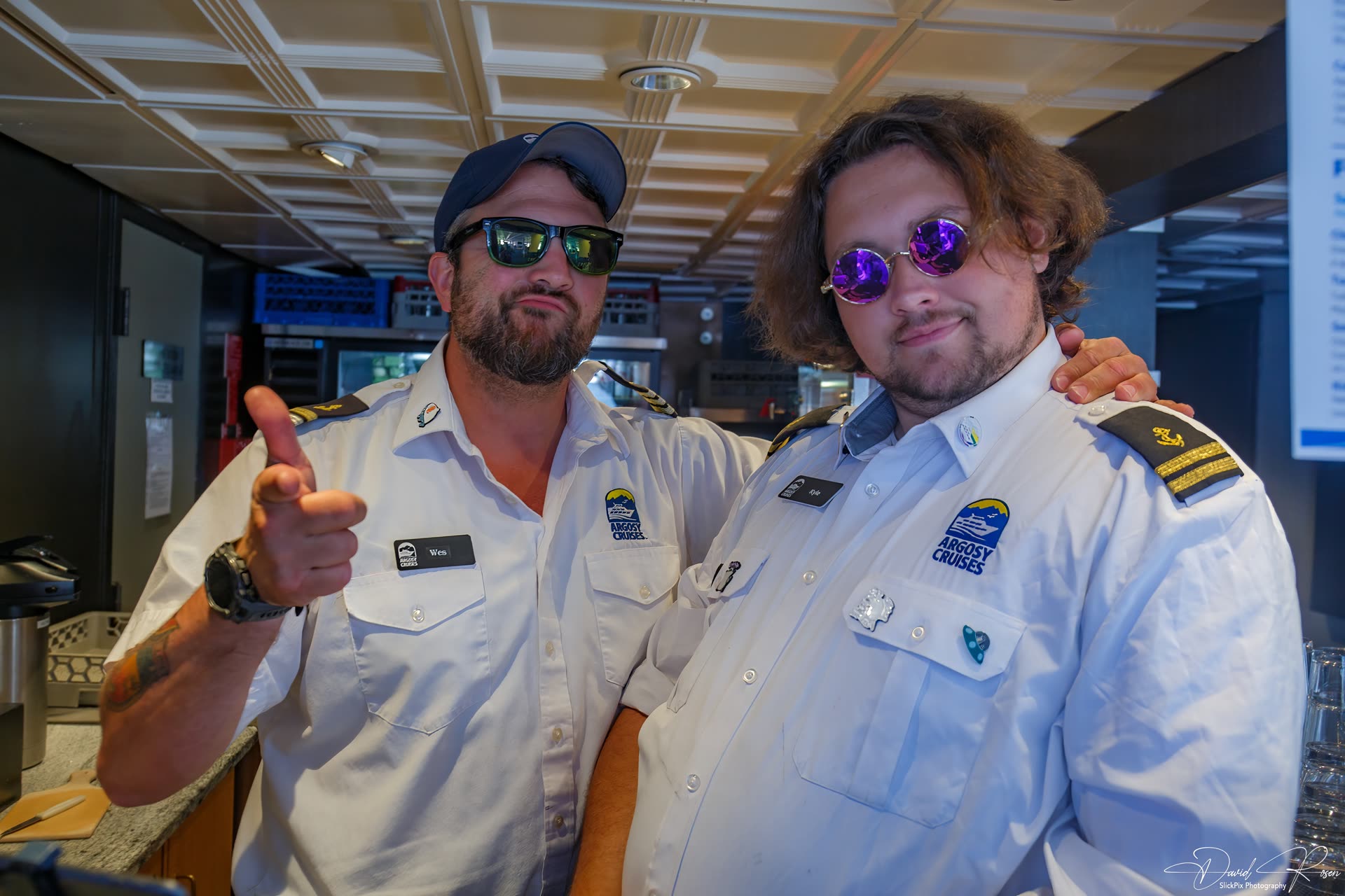 Two uniformed crew members welcome passengers aboard.