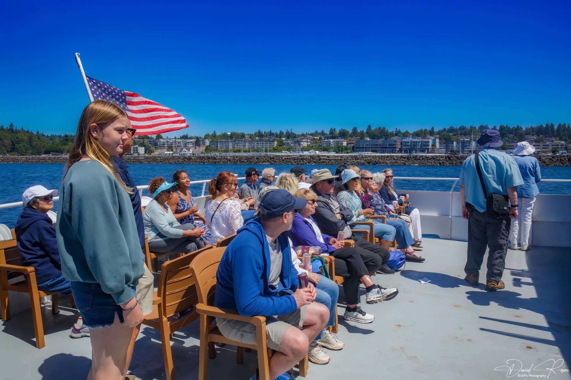 Passengers sit in rows of deck chairs while cruising on Puget Sound.