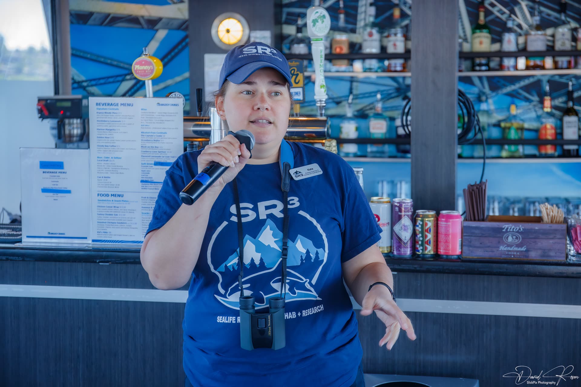 A presenter speaks into a microphone in front of the passenger cabin.