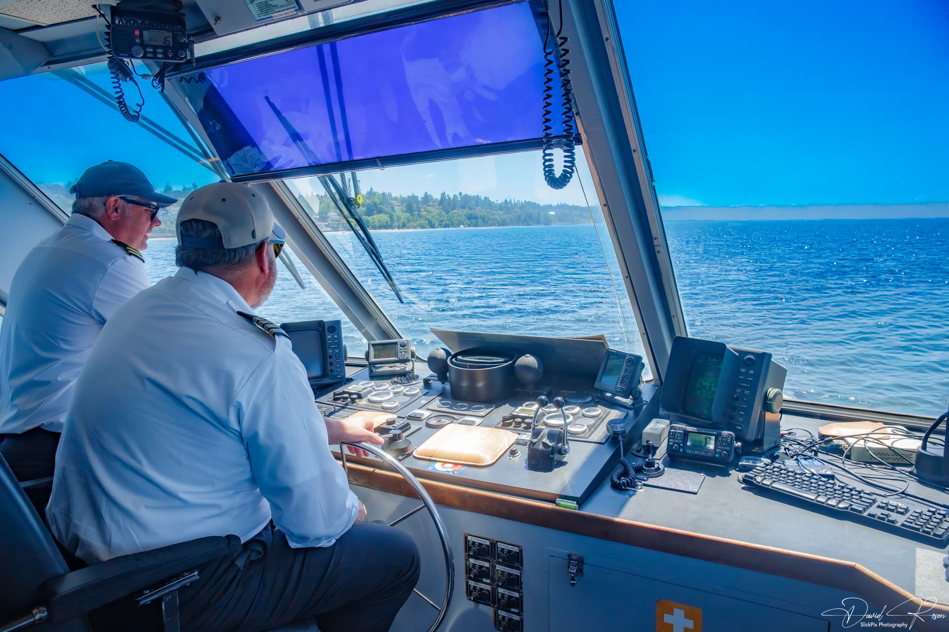 Two crew members operate the vessel from the wheelhouse.