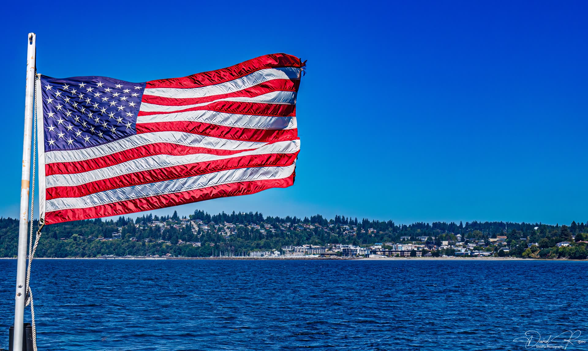 American flag flying from the vessel with shoreline in the distance.