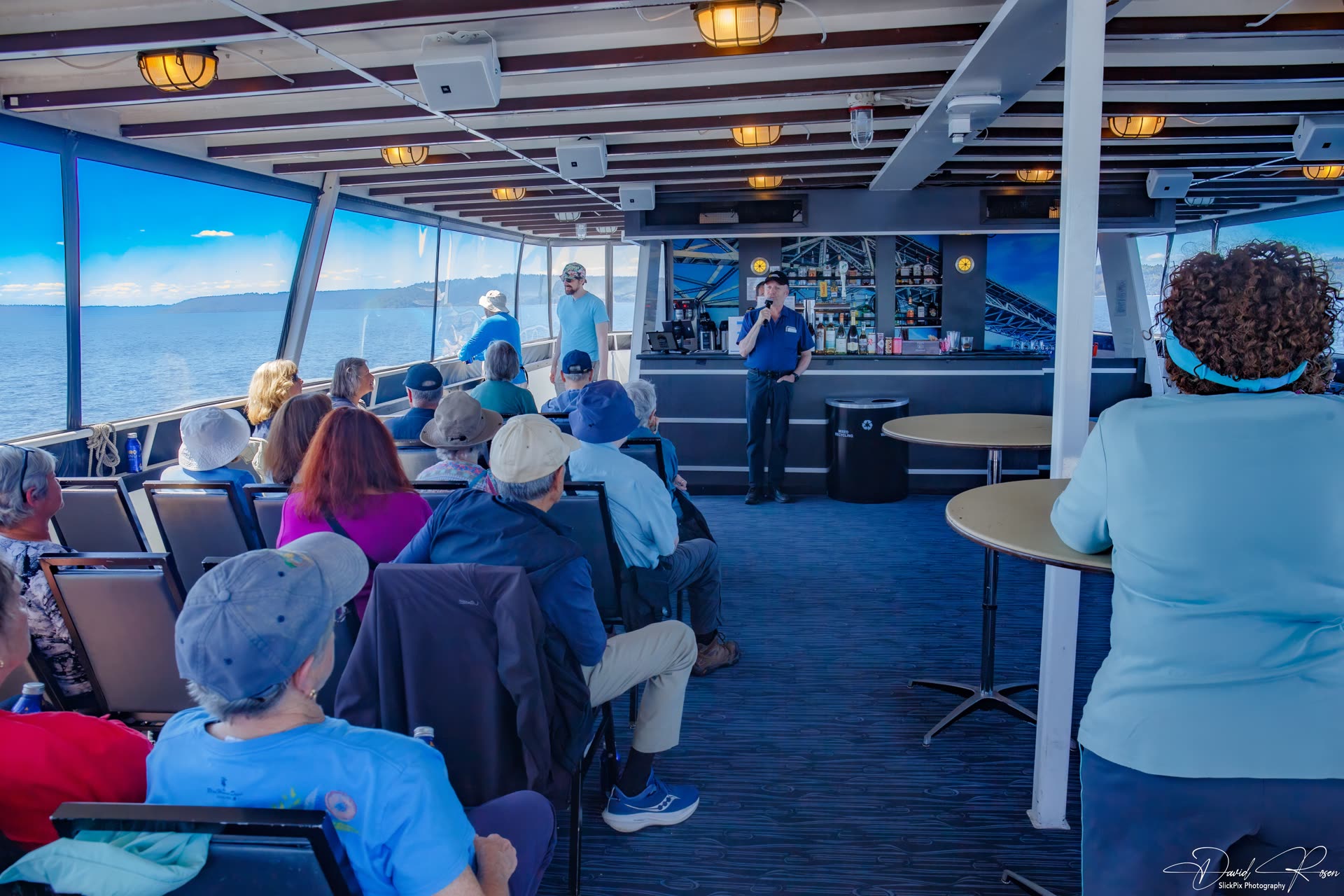 Passengers gather in the cabin while the shoreline passes outside.